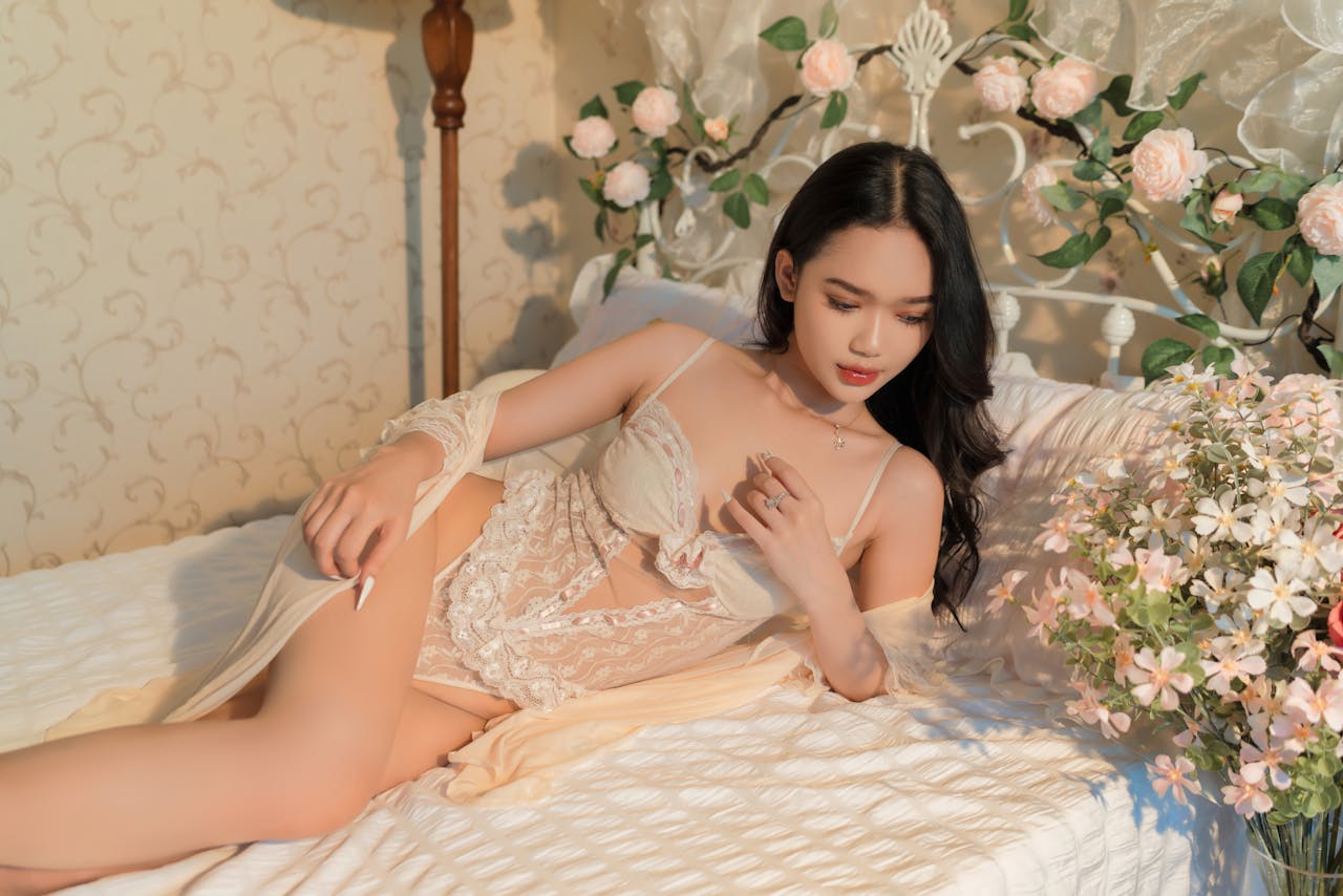 A woman in lace lingerie relaxing in a floral-decorated bedroom, exuding elegance.